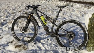 A Merida mountain bike leaning against a rock in a snowy landscape