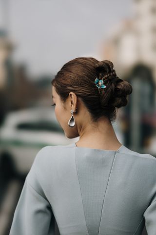 woman with a braided bun and blue hair accessories facing away from the camera