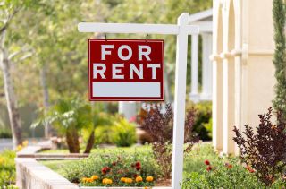 A sign saying "for rent" in front of a home.