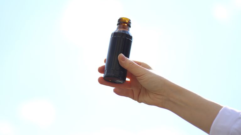Person holding an energy drink bottle in the air