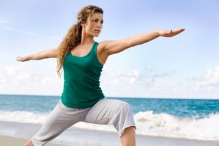 woman doing warrior pose on the beach
