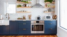 Wondering how to clean a self-cleaning oven so it looks as clean as this one? Pictured is a blue and white modern, minimalist-style space with a clean oven in the center of the room and a white basin sink