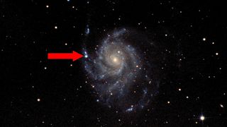 a spiral galaxy in deep space with a bright flash of light on one of its arms