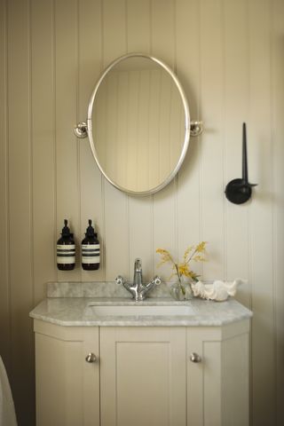 A modern neutrally decorated bathroom with wall panelled walls, a built-in vanity, and a marble sink countertop