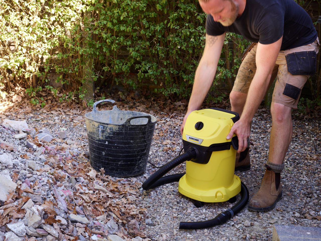 A K&auml;rcher WD 3 vacuum cleaner with a builder beginning to remove the top ready to empty