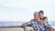 An older couple look cozy together on a boat.