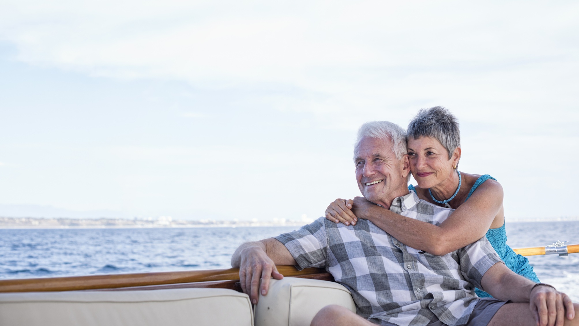 An older couple look cozy together on a boat.