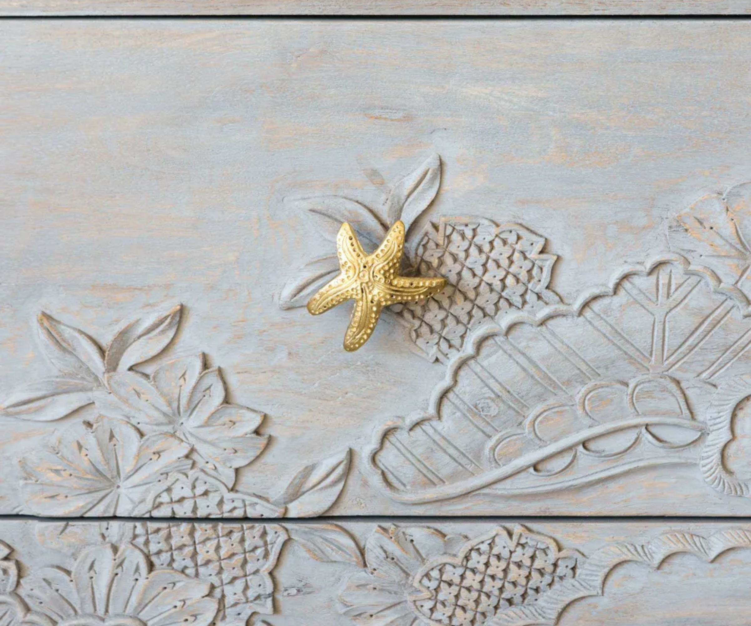 gold starfish shaped drawer knob on white distressed chest of drawers