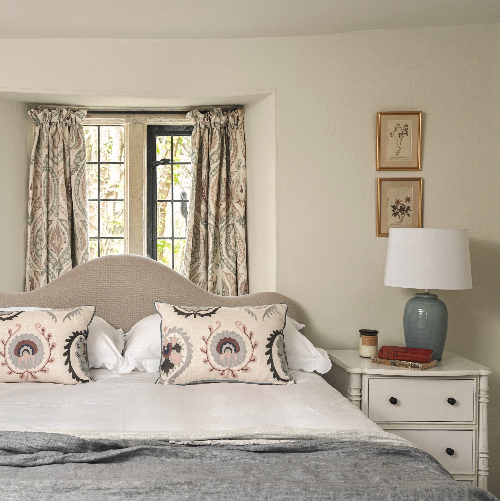 bedroom with upholstered headboard and white furniture in front of window