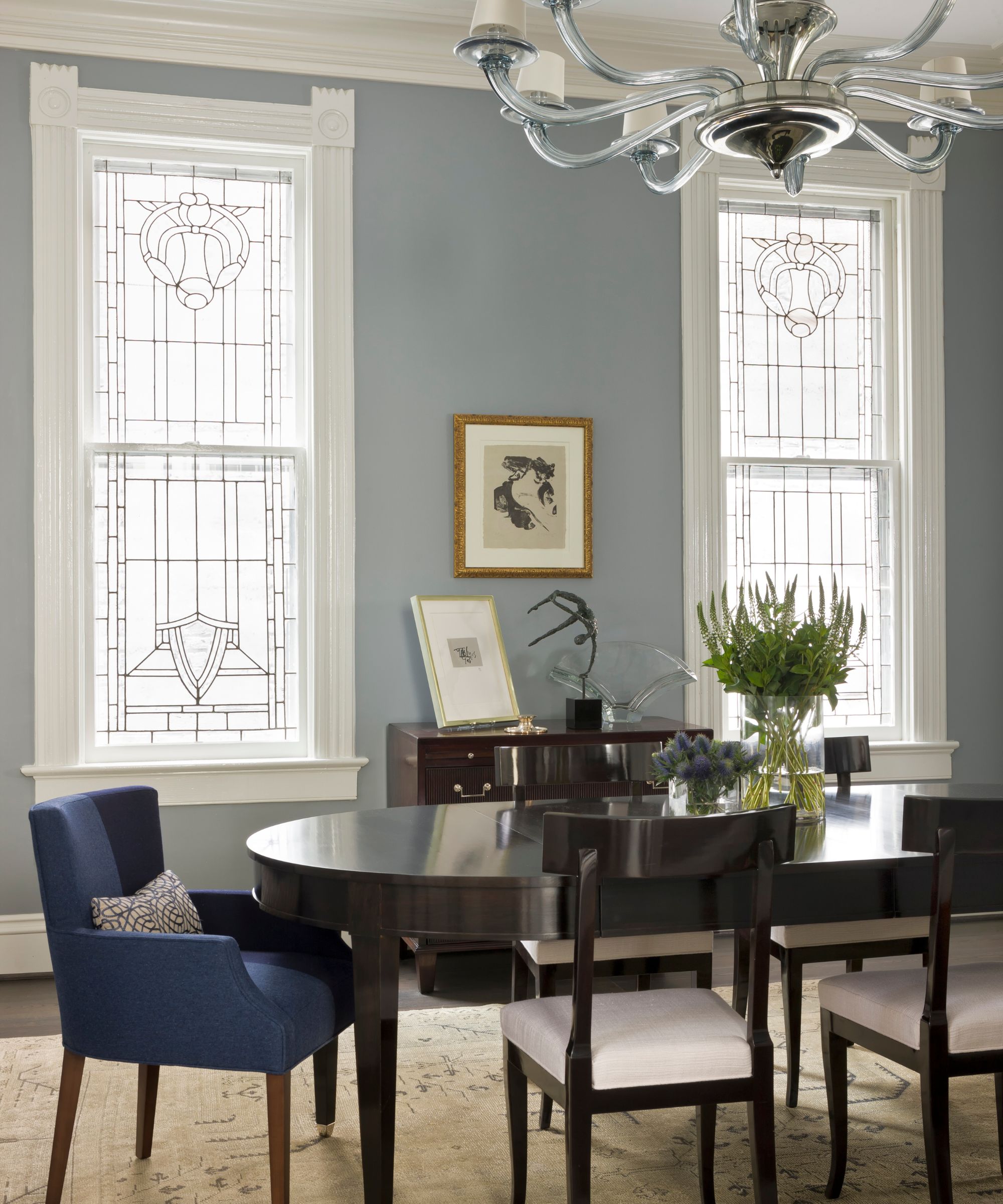 Dining room with blue walls, stained glass windows, dark wood dining table and chairs