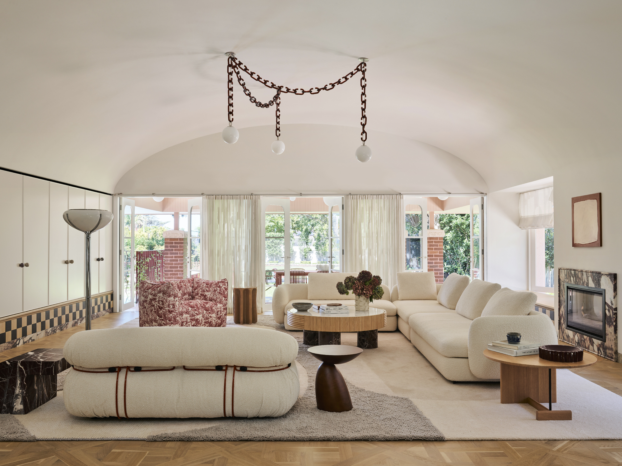 a contemporary living room with sculptural white sofas, a pendant chain light and a large rug