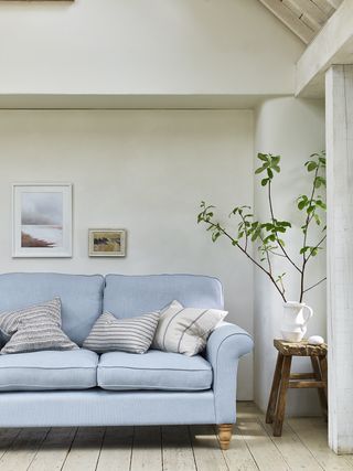 white living room with alcove and blue couch, vaulted ceiling