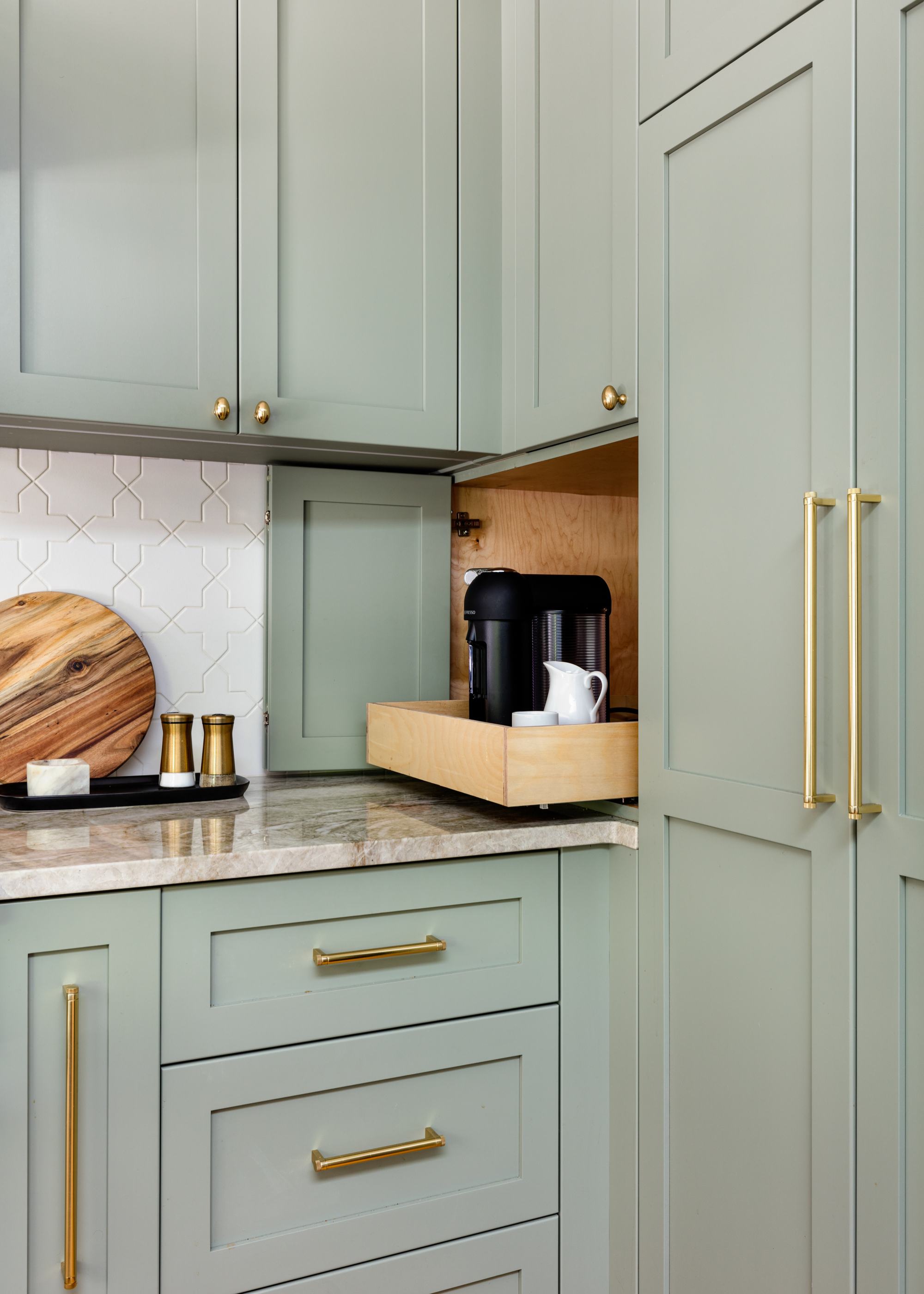 Sage green shaker style kitchen cabinets with a small appliance garage housing a coffee machine