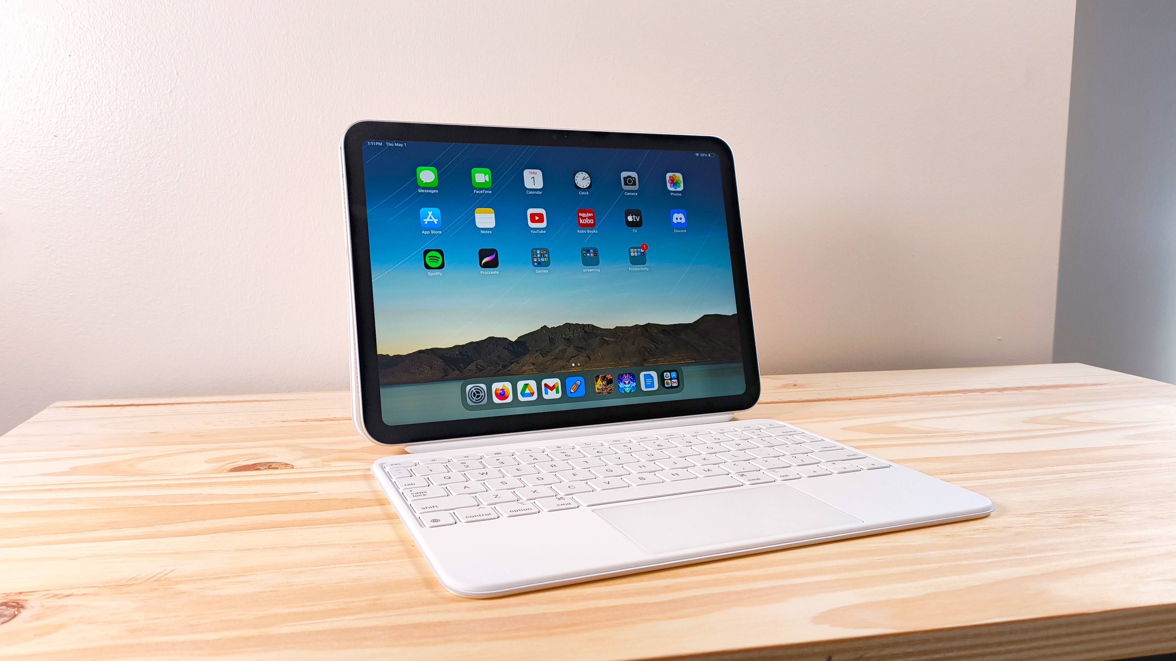 The iPad 11 propped up on a wood table connected to the Magic Keyboard Folio