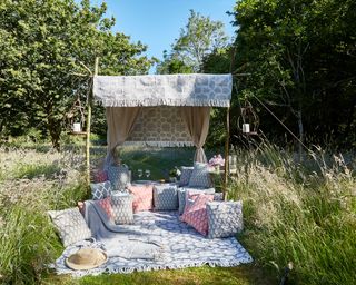 An example of garden zoning showing a garden den with a sofa under a canopy and a picnic blanket