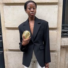 fashion influencer Sylvie Mus stands on the streets of Paris with a sharp black blazer outfit