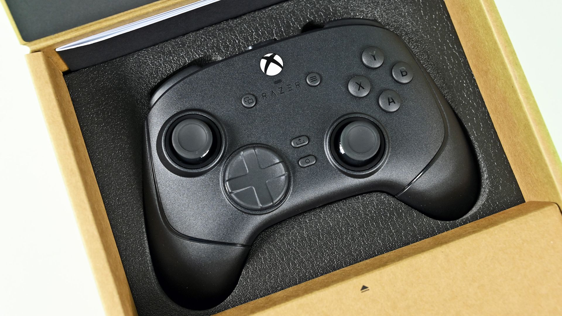Top-down view of the black Razer Wolverine controller nestled securely inside the black foam insert of its open packaging box.