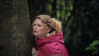Alice (Rebekah Staton) peers round a tree in The Following Events Are Based On A Pack Of Lies