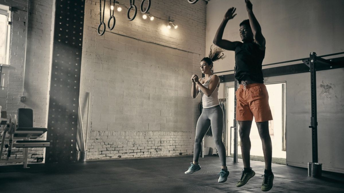 Two people perform the jump portion of burpees