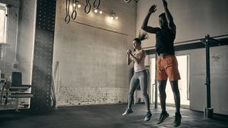 Two people perform the jump portion of burpees