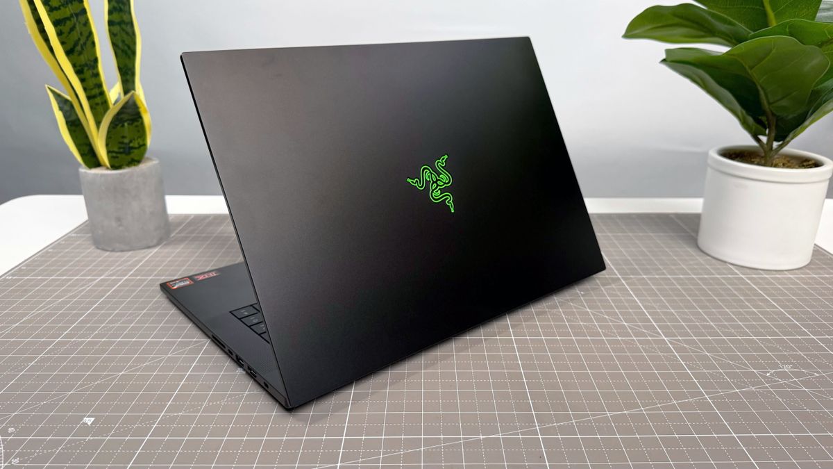 Razer Blade 16 (2025) gaming laptop, facing away from the camera on a white and beige desk against a gray backdrop.
