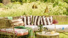 Pooky Brass Outdoor Pendant Lights hanging from a tree above a garden sofa and table set surrounded by greenery