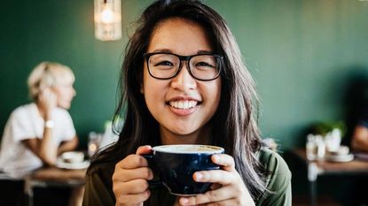 Young woman drinking coffee and smiling.