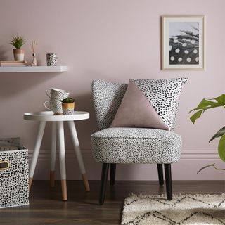 white chair with black dots design designed pillow and pink wall