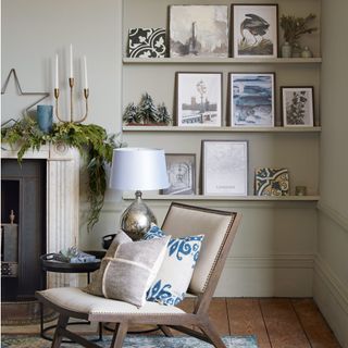alcove beside mantelpiece with grey walls and grey shelving with framed pictures, wooden flooring and blue rug