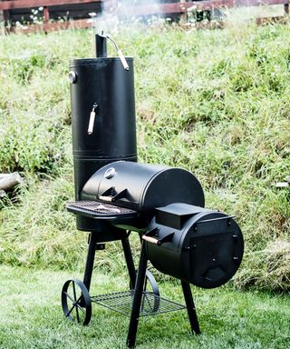 Black metal Locomotive grill with a smoker on green grass background