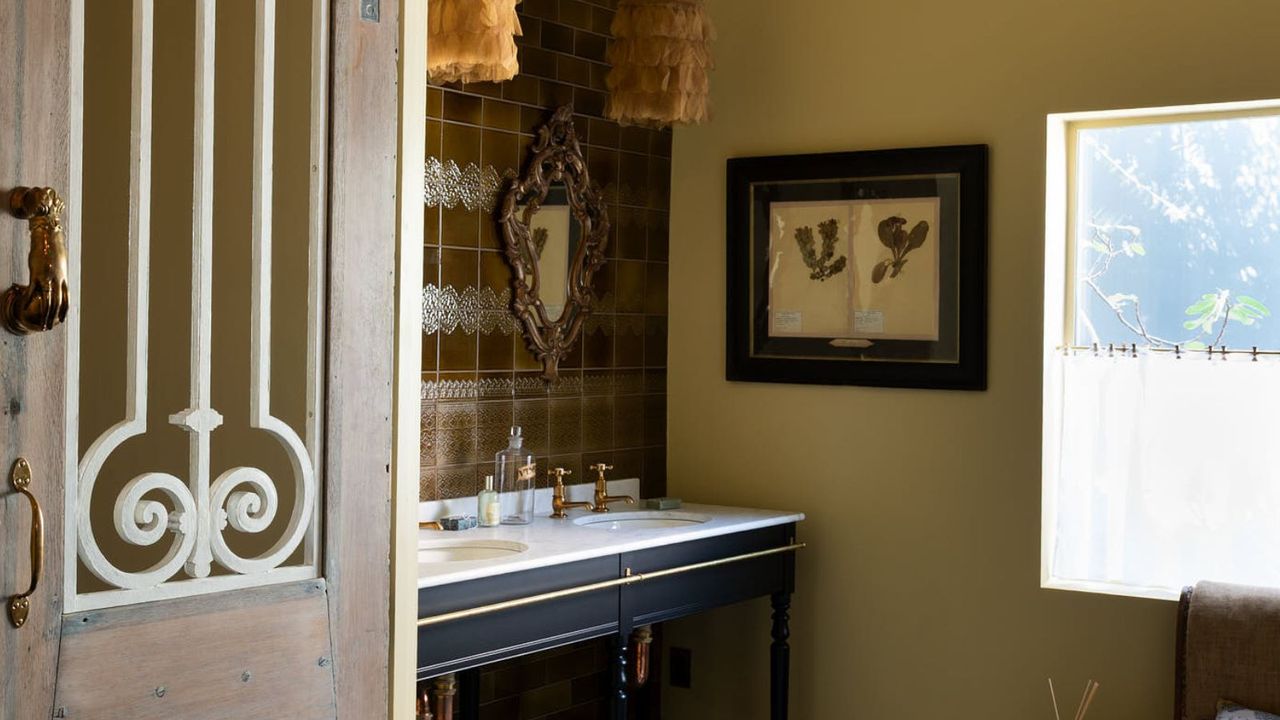 A Traditional bathroom with a double sink washstand, warm neutral walls, and vintage art
