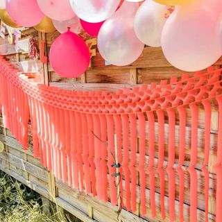 coral coloured paper streamers decorating a garden party fence
