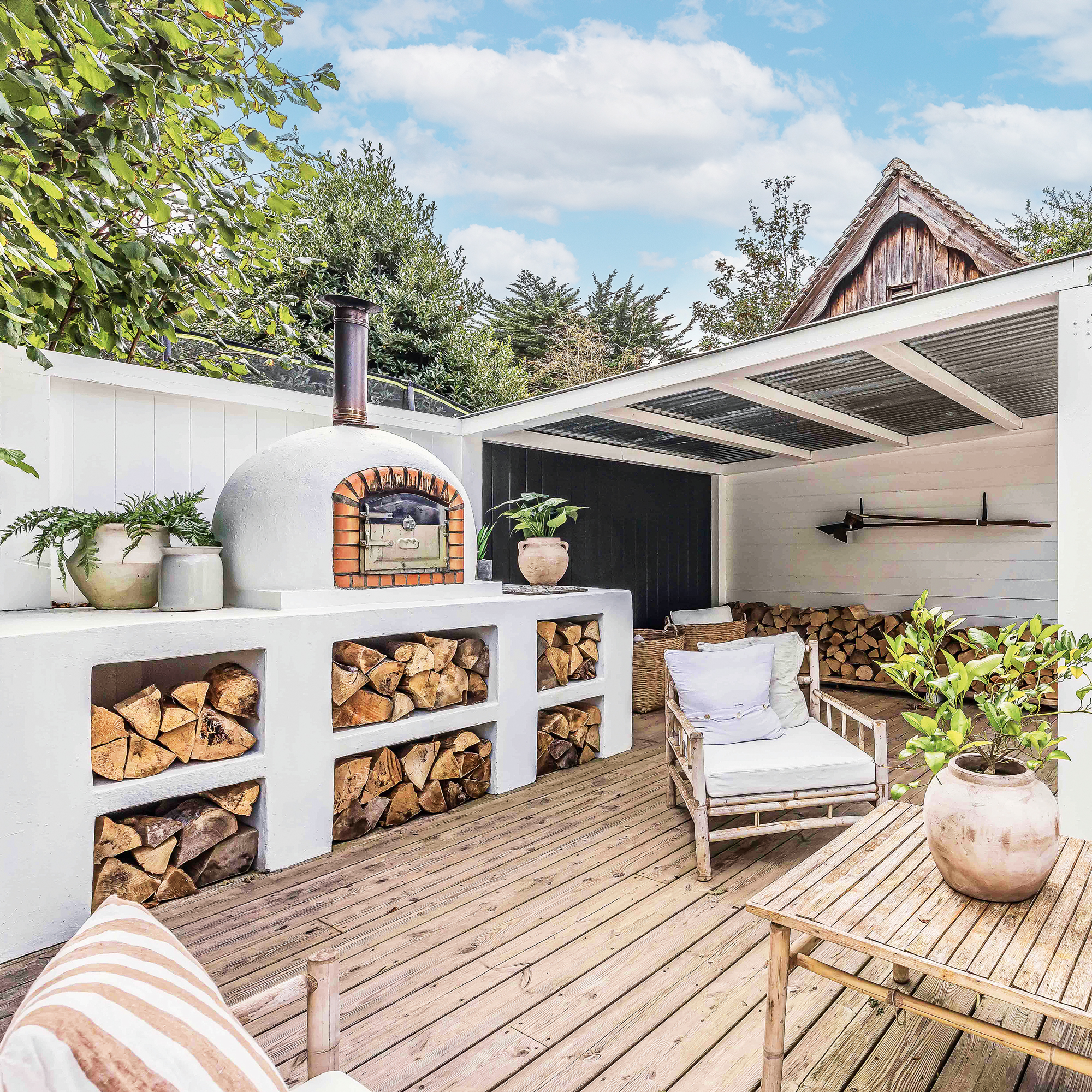 an outdoor kitchen with wood fired pizza oven and wood storage beneath