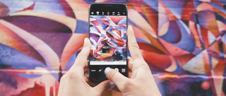 Man photographing a brightly painted wall with a cameraphone