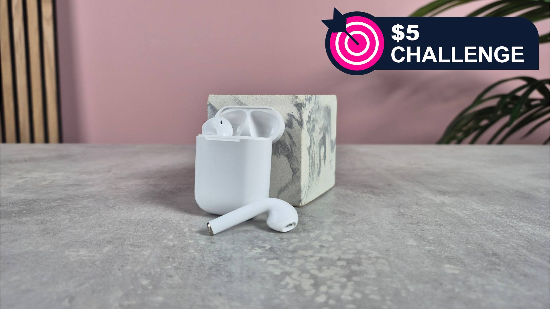 Cheap wireless earbuds against block with pink background and plant, alongside the words &#039;$5 challenge&#039;