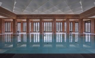 A large indoor swimming pool surrounded by large pillars and glass windows.