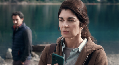 A woman holds a phone and looks concerned in Caught