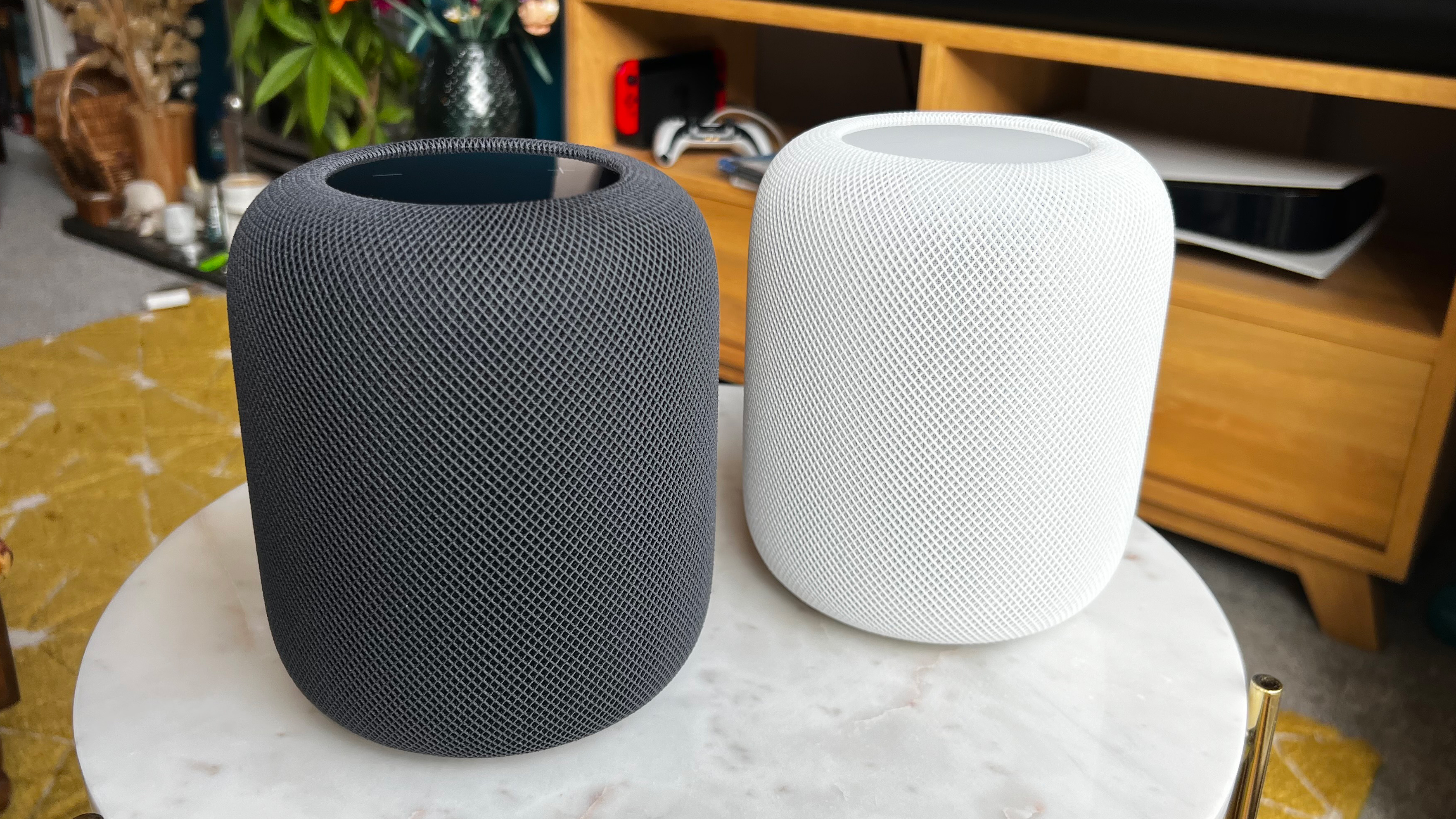 Two Apple HomePod 2 speakers in black and white on a marble shelf in a home