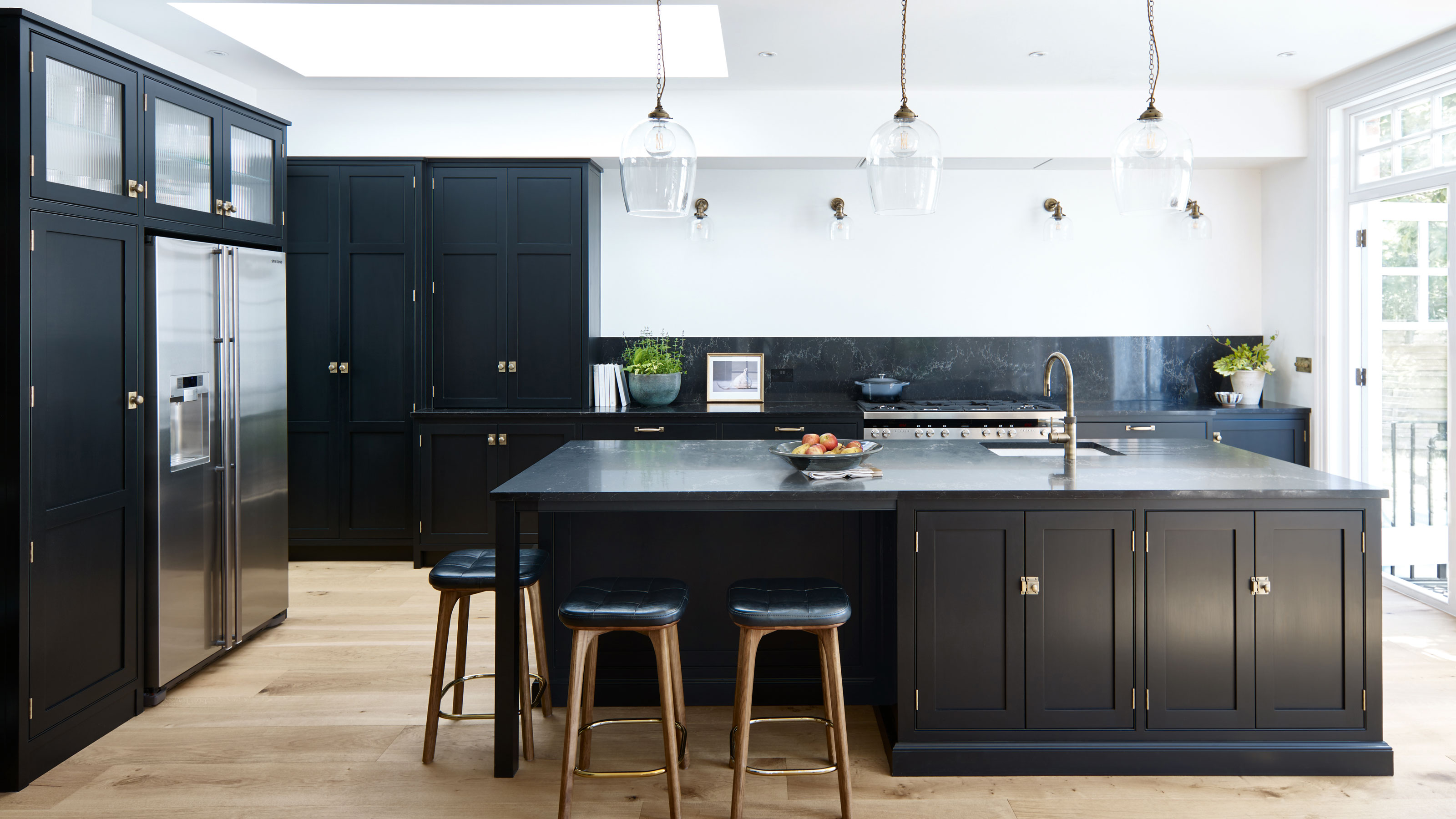 Black kitchen with large kitchen island and glass pendant lights