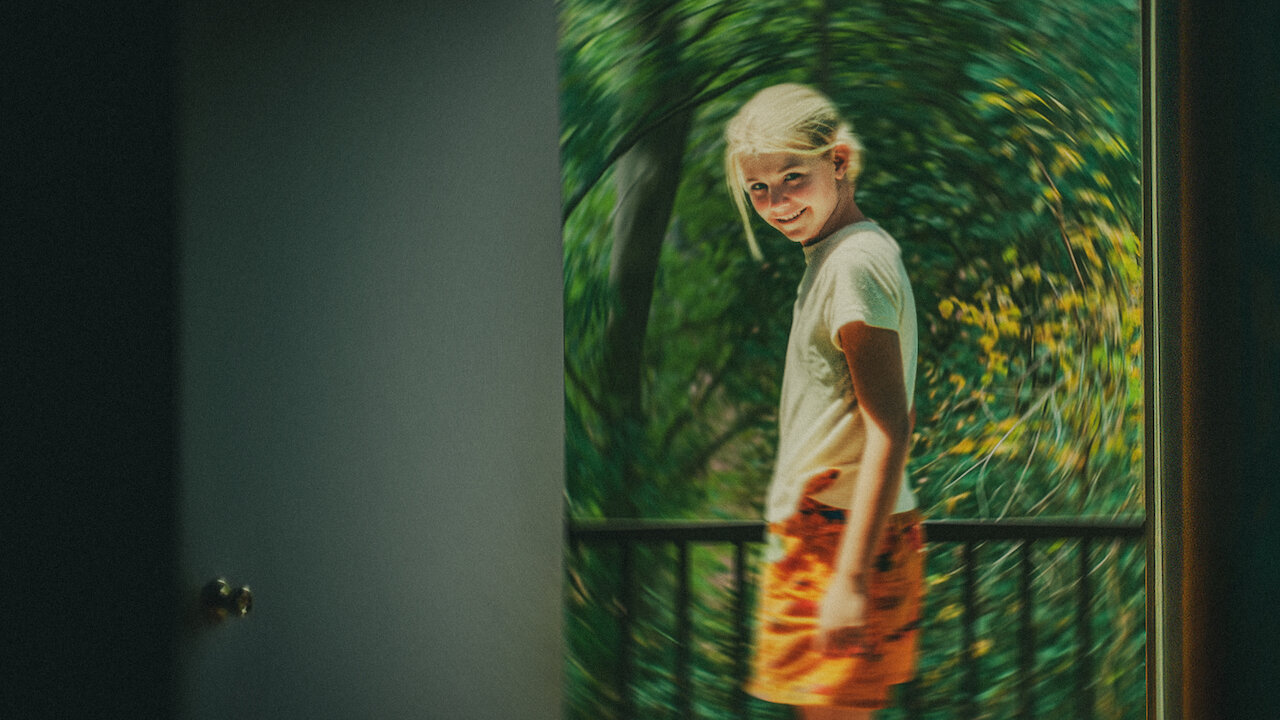 a still of a smiling blonde girl on a balcony in a still from the true crime documentary kidnapped elizabeth smart