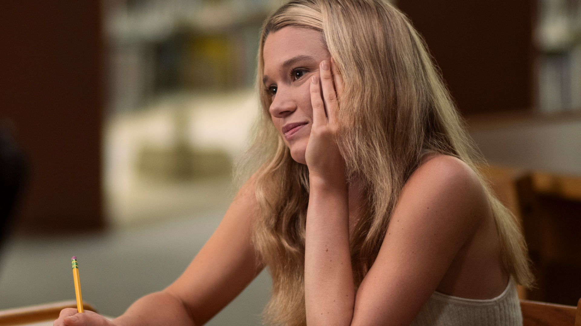 rain spencer as taylor resting her head on her chin smiling and writing in the summer i turned pretty season 3