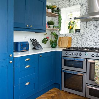 blue kitchen with white worktops and stainless steel oven