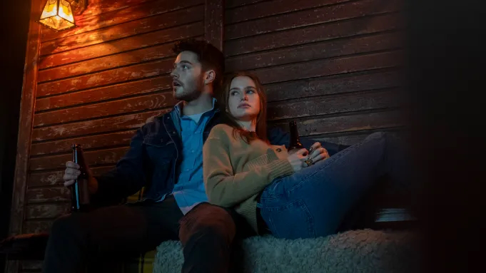 a man and a woman sit on a couch in front of a brick wall