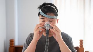 A man fitting a CPAP mask to help his central sleep apnea