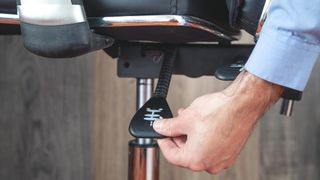 A hand adjusting an office chair's height