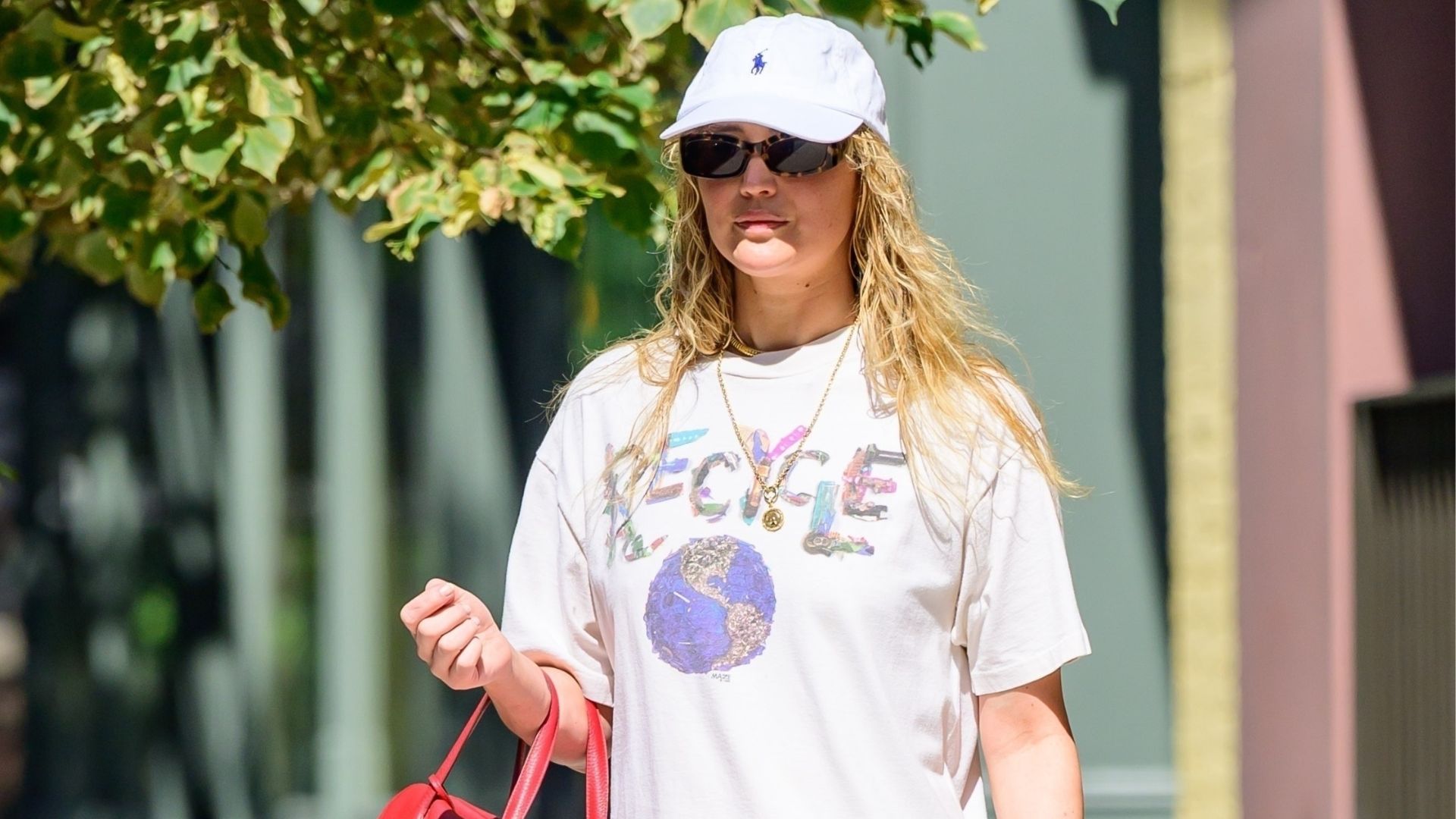 Jennifer Lawrence steps out in New York styling 3/4 length lace-trim trousers with a lace top and an oversized graphic tee. She styled her look with a red handbag and tan toe sandals.