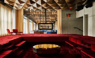 Sunken living room with red velvet upholstery and faceted coffee table