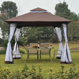 Large gazebo with curtains and a brown top covers outdoor dining setup on a garden lawn