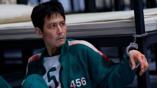 Player 456 handcuffed to a bed in Squid Game Season 3. 