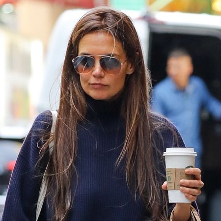 Katie Holmes spotted in New York City wearing a navy blue turtleneck, plaid pants, and black boots while getting a coffee and picking up Eataly. 